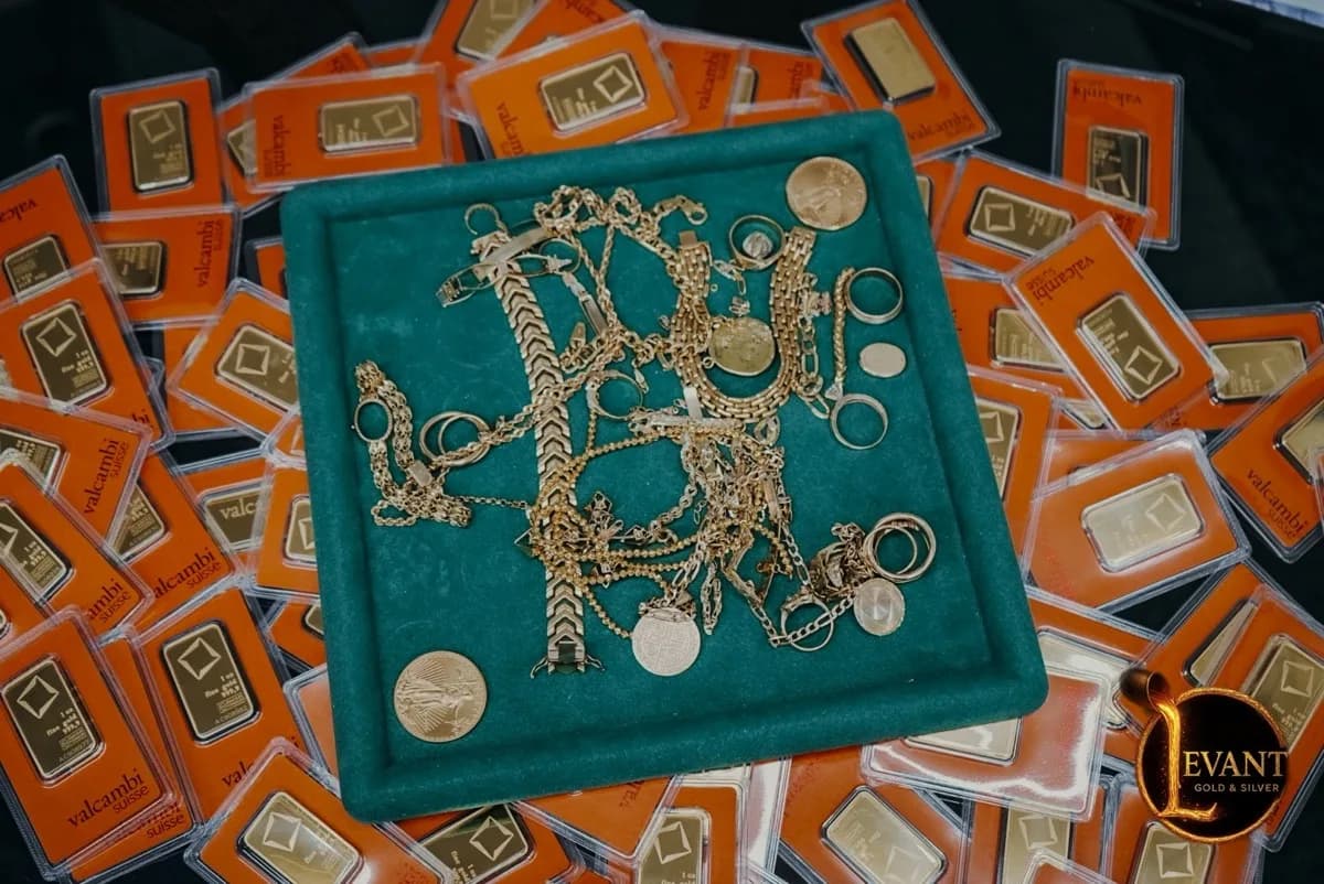 Tray of gold chains, rings, and coins on PAMP gold bars